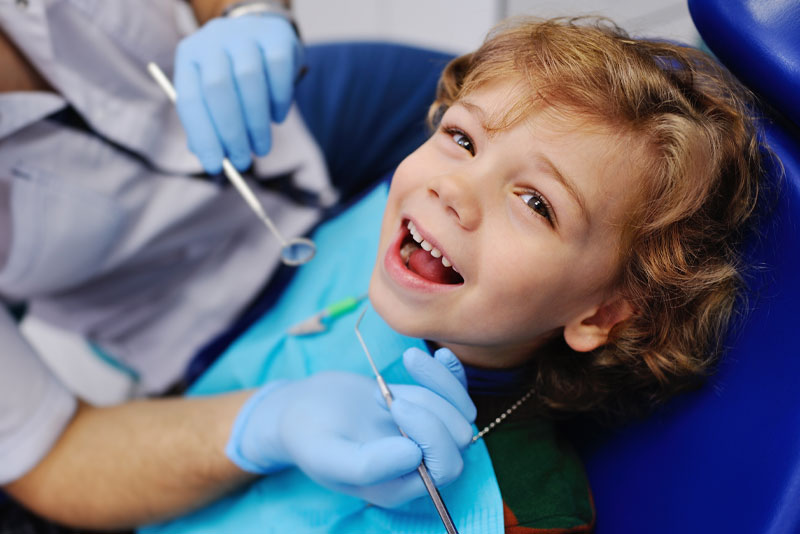 a pediatric dental patient smiling as he gets treated with a wisdom tooth removal.
