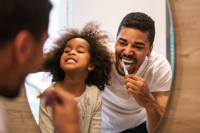 an image of a father and daughter brushing their teeth at Esteem Dental in Winter Garden, FL.