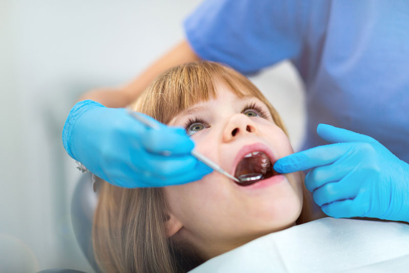 a kid getting her baby teeth checked out during a pediatric dentistry procedure.